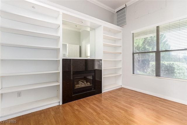 unfurnished living room with a fireplace, baseboards, wood finished floors, and ornamental molding