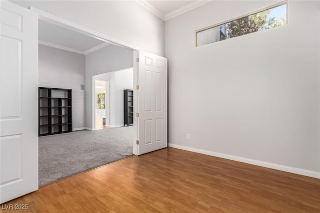 spare room featuring ornamental molding, baseboards, and wood finished floors