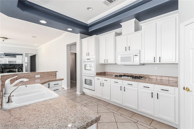 kitchen with white appliances, visible vents, white cabinets, crown molding, and a sink