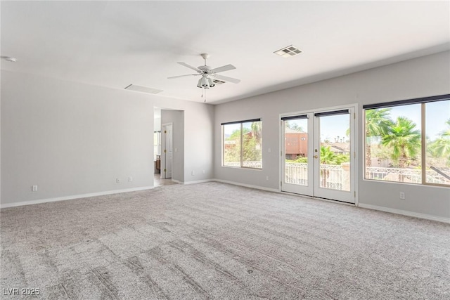 carpeted empty room featuring baseboards, visible vents, and a ceiling fan