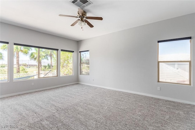 carpeted spare room with visible vents, ceiling fan, and baseboards