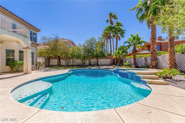 view of swimming pool featuring a fenced backyard, a pool with connected hot tub, and a patio