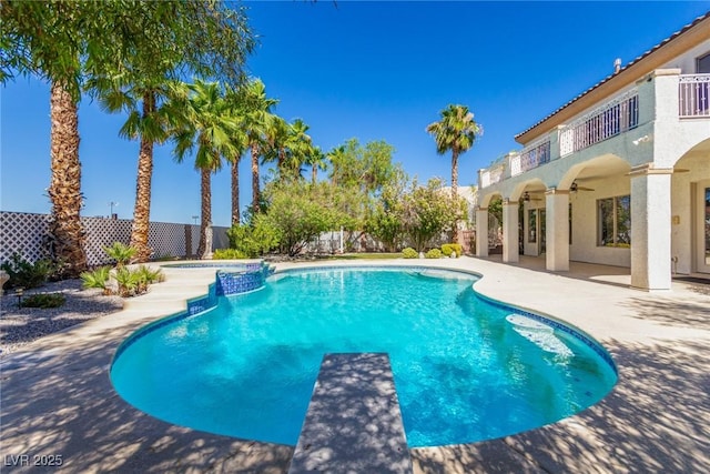 view of swimming pool featuring a patio, a pool with connected hot tub, ceiling fan, a fenced backyard, and a diving board