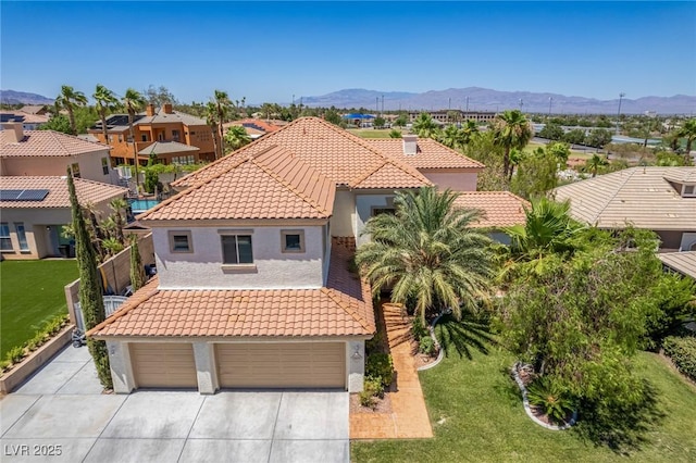 mediterranean / spanish-style home featuring a tiled roof, concrete driveway, a mountain view, and stucco siding