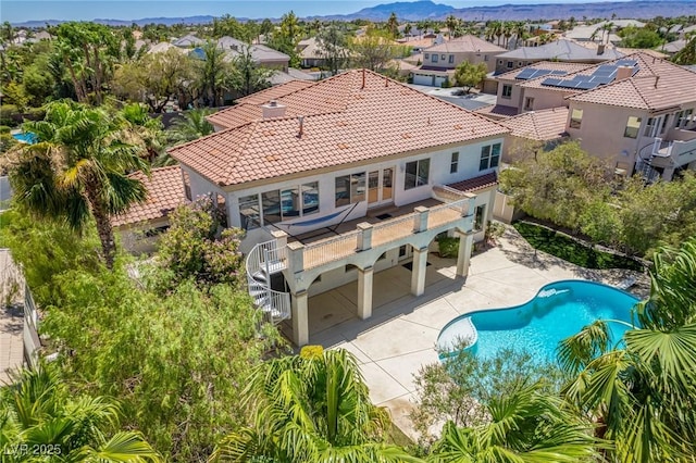 rear view of property featuring a patio, a tiled roof, a fenced in pool, a residential view, and stucco siding