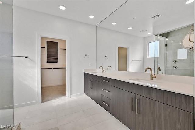 bathroom with double vanity, a shower stall, visible vents, and a sink