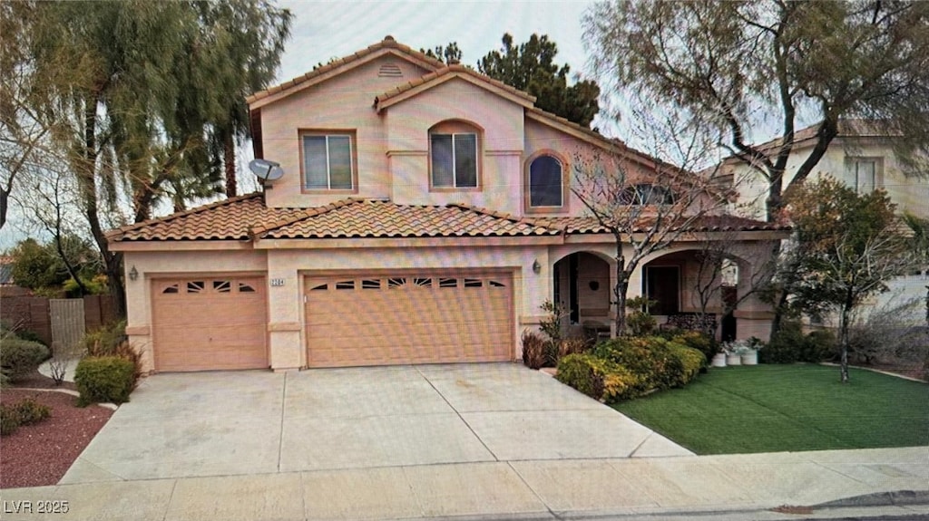 mediterranean / spanish-style house featuring a tile roof, a front yard, concrete driveway, and stucco siding