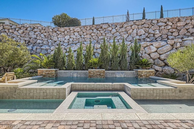 view of pool with fence and an in ground hot tub