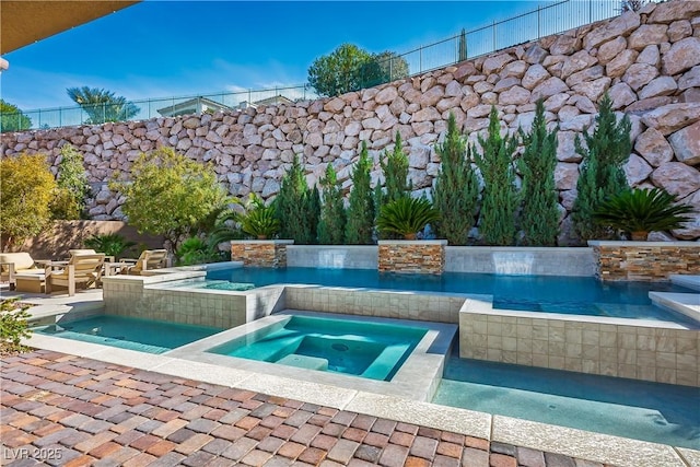 view of pool with a patio area, fence, and an in ground hot tub