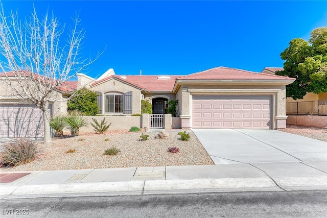 view of front facade with a garage, concrete driveway, a tile roof, fence, and stucco siding