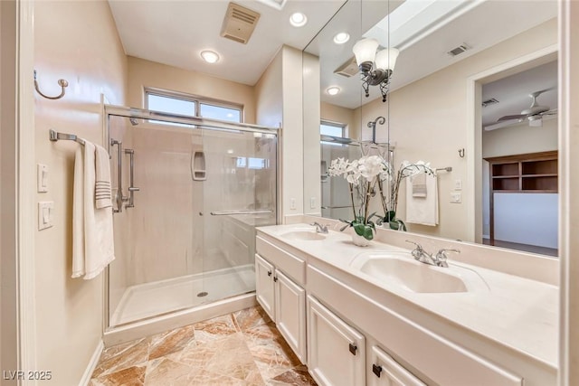 full bath featuring double vanity, a shower stall, a ceiling fan, and a sink