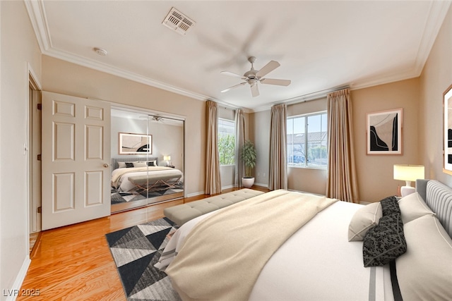 bedroom with visible vents, crown molding, and light wood finished floors