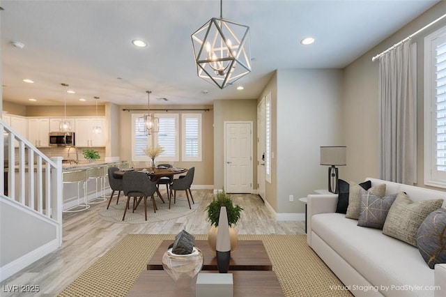 living area with recessed lighting, light wood-style flooring, baseboards, and an inviting chandelier