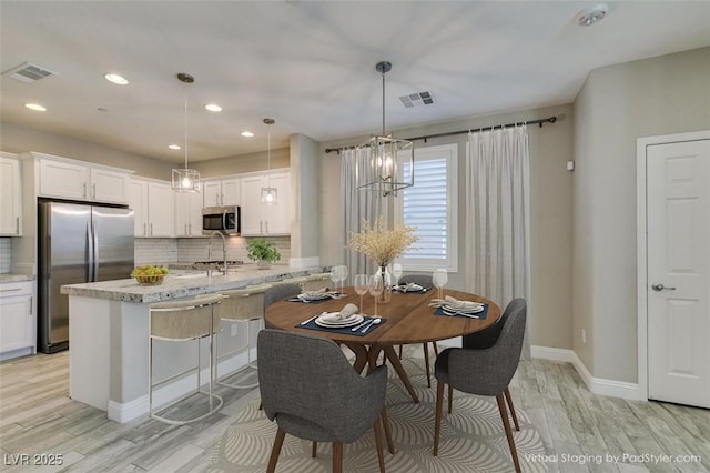 dining area featuring light wood-style floors, visible vents, and baseboards