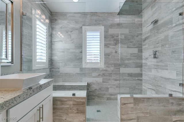 bathroom featuring a wealth of natural light, tiled shower, and vanity