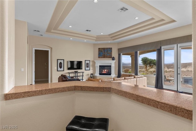 kitchen with visible vents, recessed lighting, a raised ceiling, and a glass covered fireplace