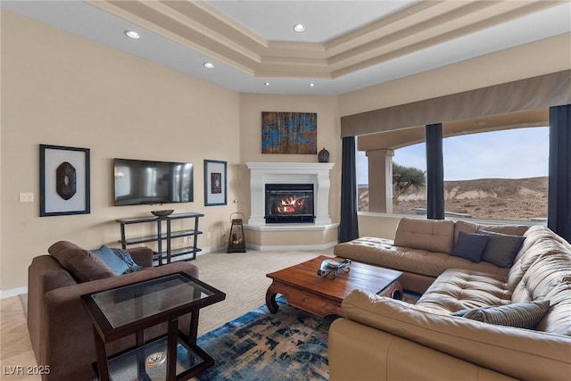 carpeted living area with a glass covered fireplace, recessed lighting, a raised ceiling, and baseboards