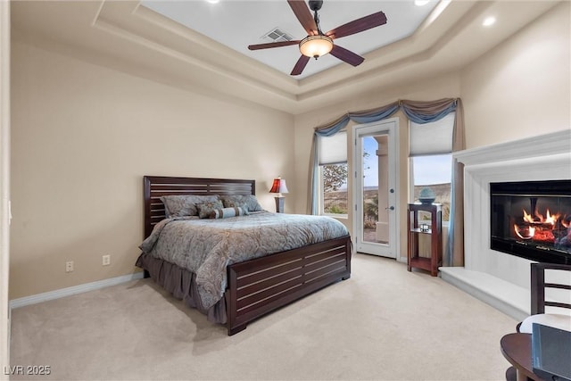 bedroom with a tray ceiling, access to exterior, visible vents, and light carpet