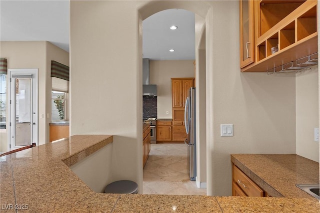 kitchen featuring recessed lighting, stainless steel appliances, arched walkways, and tile counters