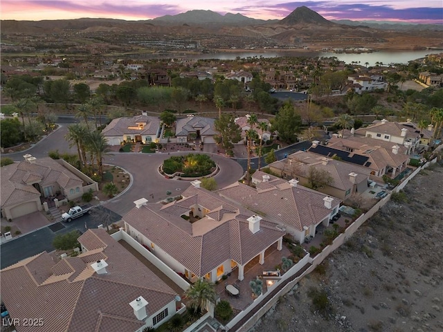 aerial view at dusk featuring a residential view and a water and mountain view