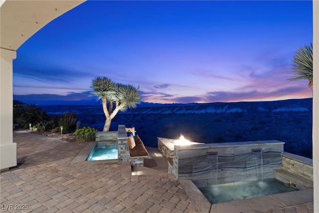 pool at dusk with a patio and a mountain view