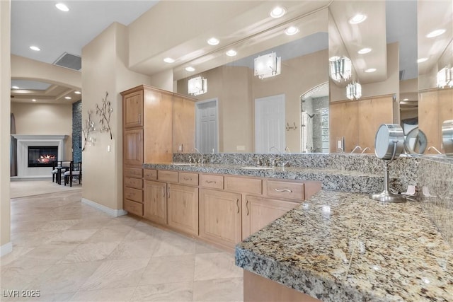 full bathroom with a shower stall, baseboards, recessed lighting, a glass covered fireplace, and vanity