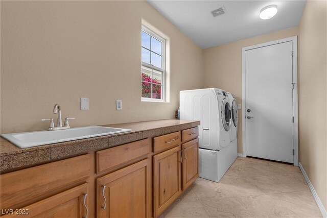 laundry room with visible vents, a sink, washing machine and dryer, cabinet space, and baseboards