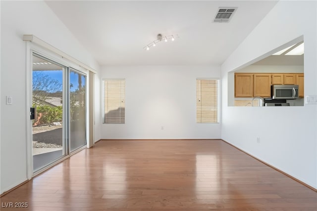 unfurnished living room with lofted ceiling, visible vents, and wood finished floors