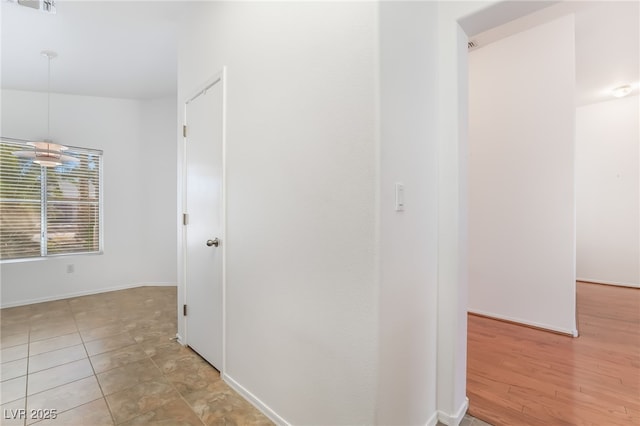 corridor with visible vents, baseboards, and light tile patterned floors