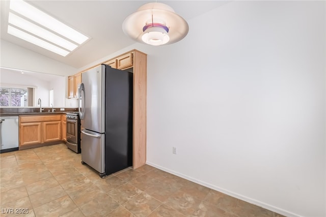 kitchen with stainless steel appliances, lofted ceiling, light brown cabinetry, a sink, and baseboards