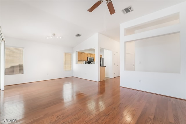 unfurnished living room with a ceiling fan, visible vents, vaulted ceiling, and light wood finished floors