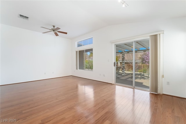 empty room featuring a ceiling fan, visible vents, vaulted ceiling, and wood finished floors