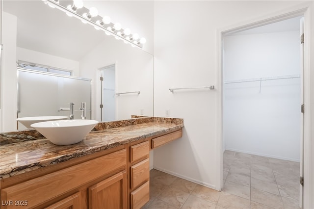 bathroom with a spacious closet, baseboards, and vanity