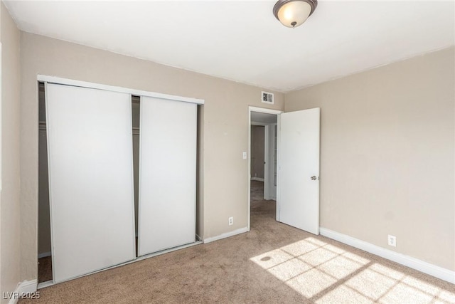 unfurnished bedroom with carpet, a closet, visible vents, and baseboards