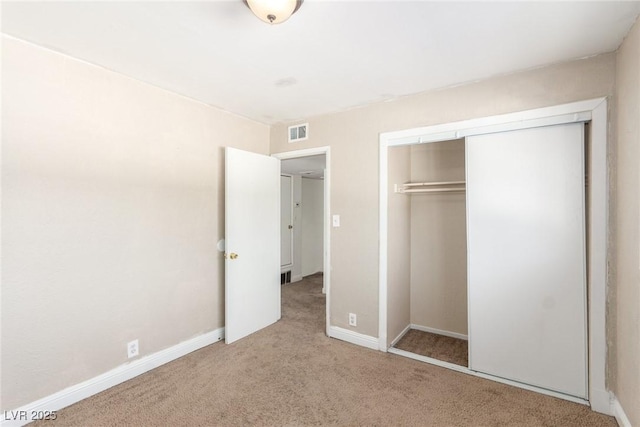 unfurnished bedroom with baseboards, carpet, visible vents, and a closet