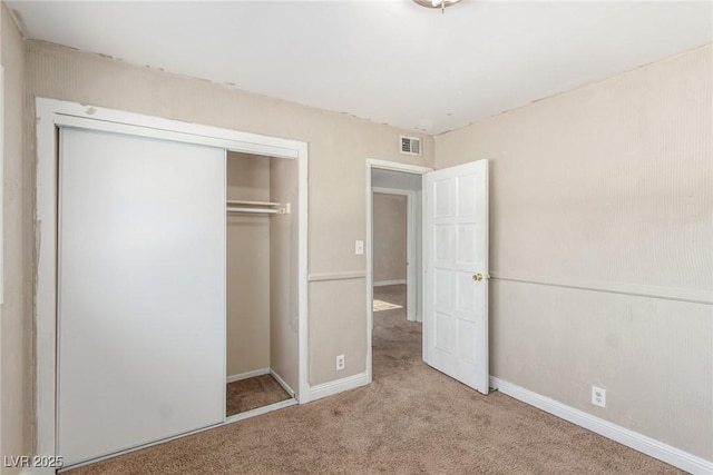 unfurnished bedroom with a closet, carpet flooring, visible vents, and baseboards