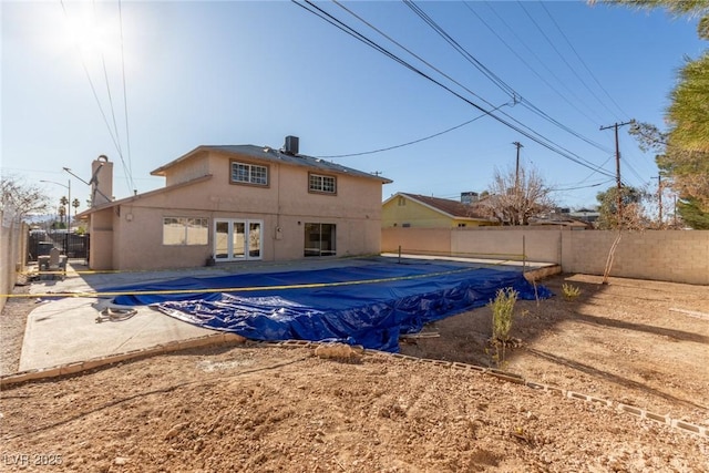 back of property with a fenced in pool, a patio, a fenced backyard, french doors, and stucco siding