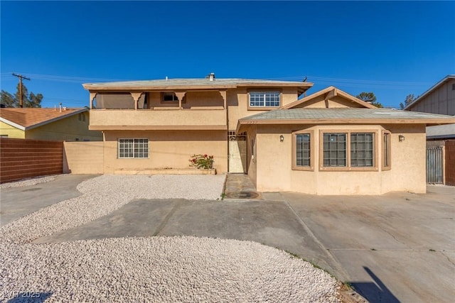 view of front of property with a patio area, fence, and stucco siding