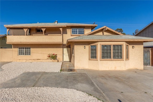 view of front of house with a patio area, fence, and stucco siding