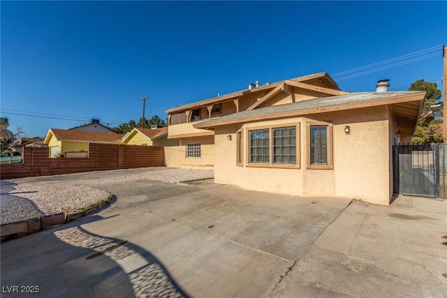 rear view of property with a patio area, fence, and stucco siding