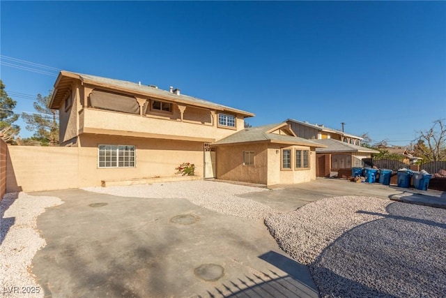 rear view of property featuring stucco siding, a patio, and fence