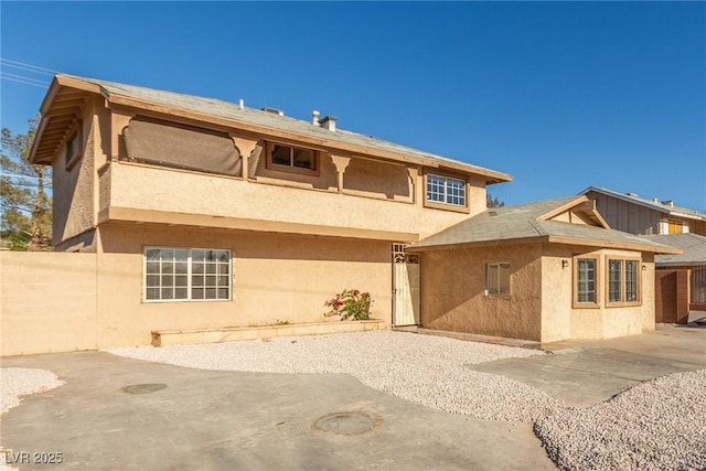 rear view of property with a patio area, fence, and stucco siding