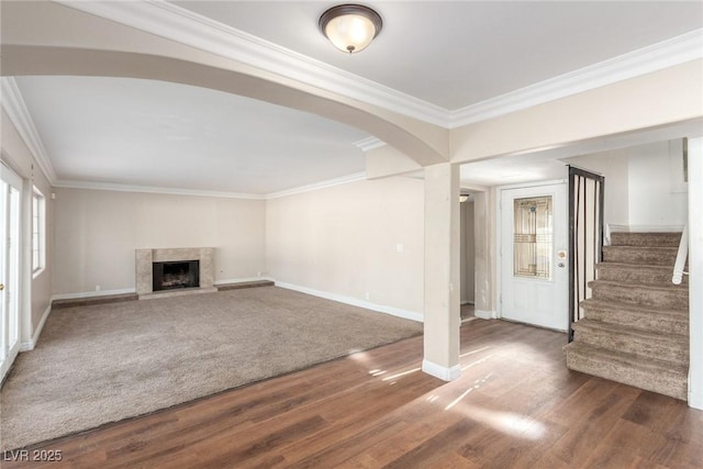 unfurnished living room with stairs, ornamental molding, and wood finished floors