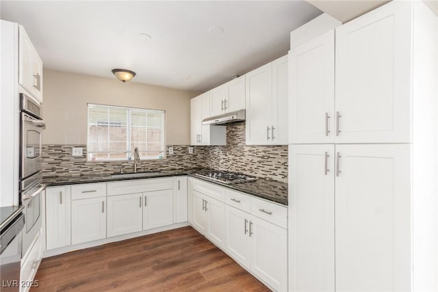 kitchen featuring dark wood-style floors, stainless steel appliances, white cabinets, a sink, and under cabinet range hood