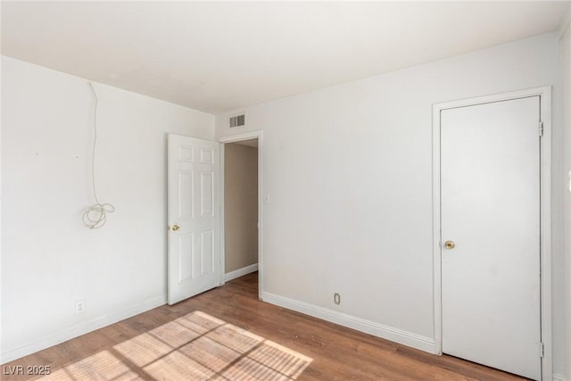 unfurnished room featuring wood finished floors, visible vents, and baseboards