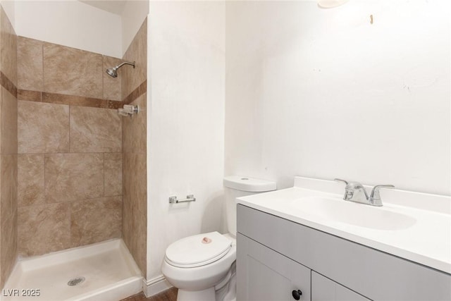 bathroom featuring toilet, tiled shower, and vanity