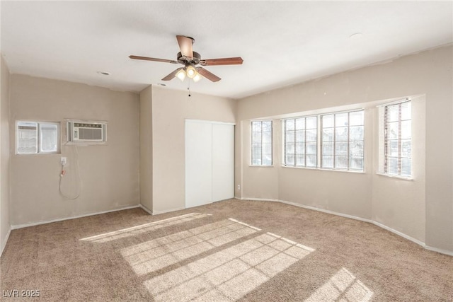 carpeted spare room with plenty of natural light, baseboards, ceiling fan, and an AC wall unit