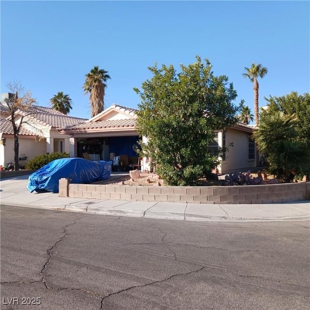 view of front of house featuring concrete driveway, an attached garage, a tile roof, and stucco siding