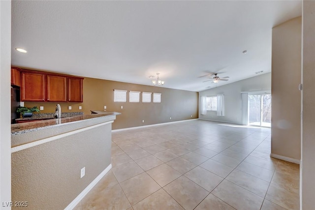 kitchen with light tile patterned floors, baseboards, open floor plan, vaulted ceiling, and ceiling fan with notable chandelier