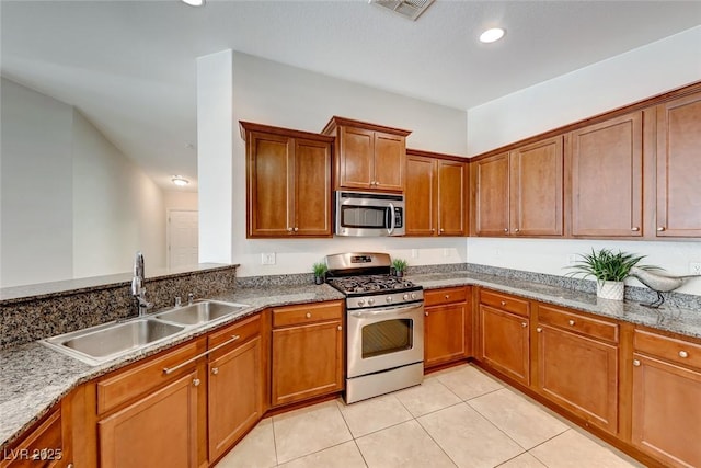 kitchen with appliances with stainless steel finishes, brown cabinetry, visible vents, and a sink